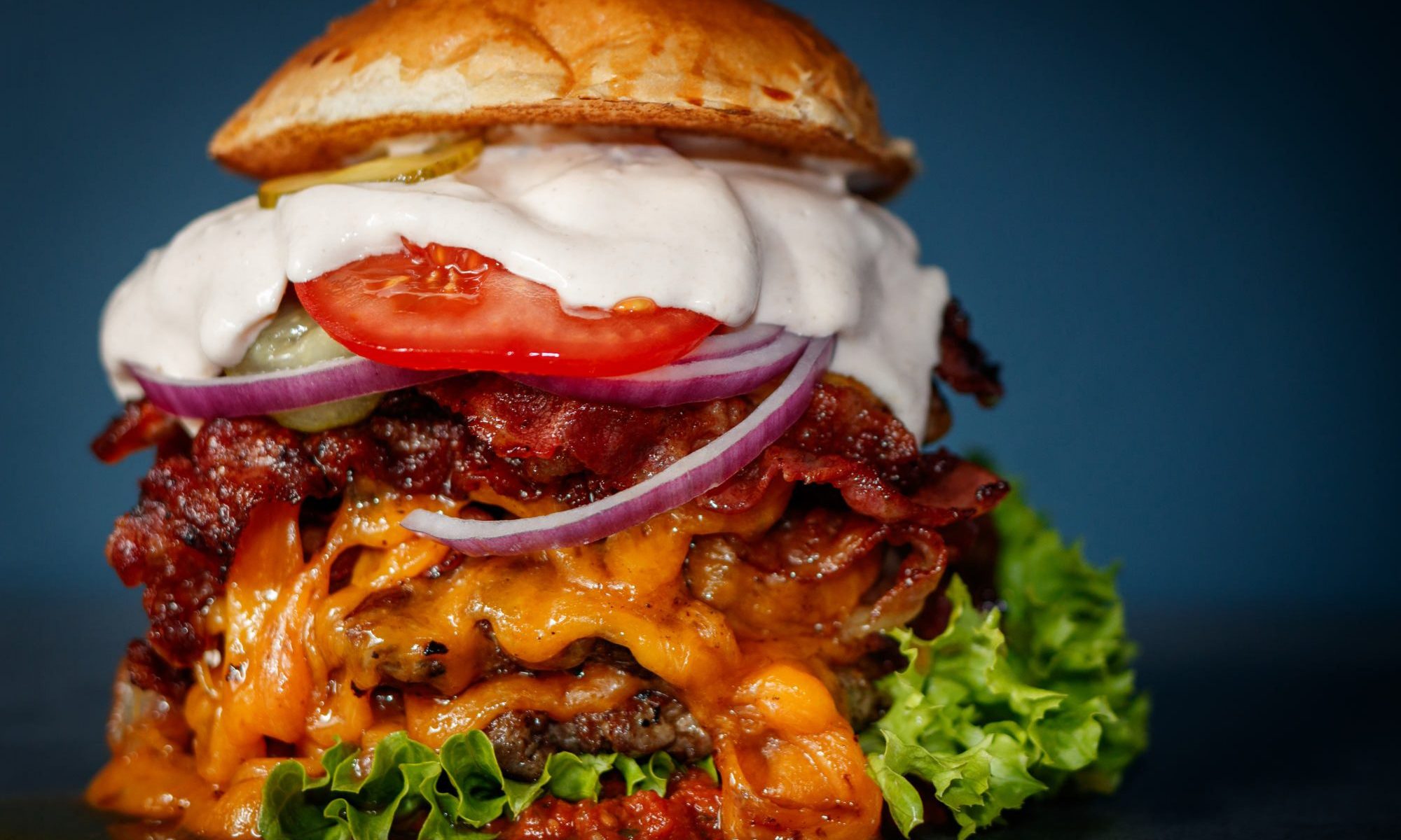 Doppeldecker-Burger mit Cheddar, Bacon, Zwiebeln und Sauce